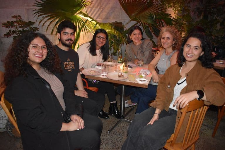 Community members sharing conversation around a table at an evening event.